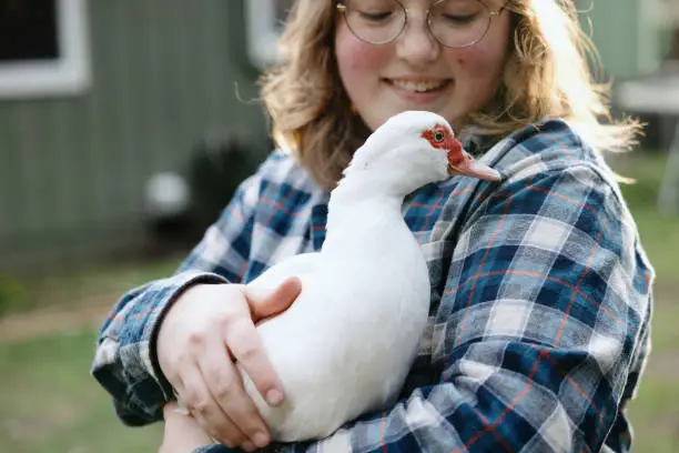 Photo of Young Woman Feeding Pet Duck