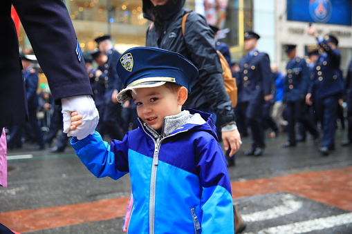 New York, New York - March 17, 2022: The son of a New York City police officer marches with dad in the St. Patrick's Day parade in New York.