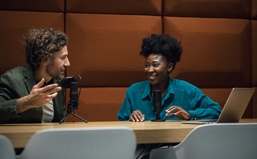 Two young hosts recording a podcast episode in a modern recording studio.