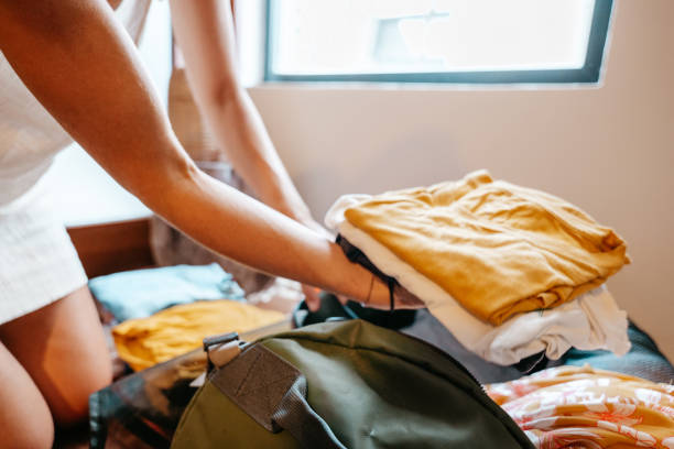 istock Young woman packing clothes in a backpack ready to leave for a trip 1386073300