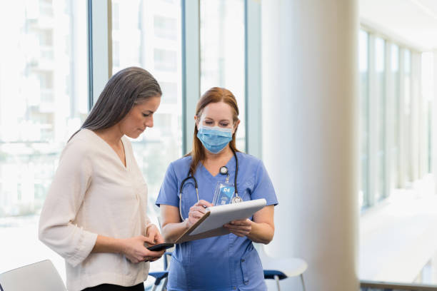 istock Woman uses phone for notes as masked surgeon reviews chart 1386085661