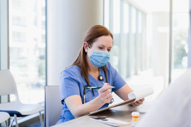 istock Nurse with protective mask takes time to update medical record 1386085673