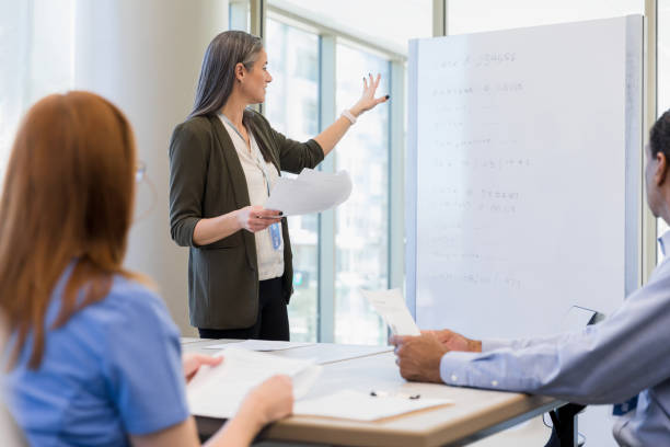 istock Female financial advisor or administrator gestures to information on whiteboard 1386085693