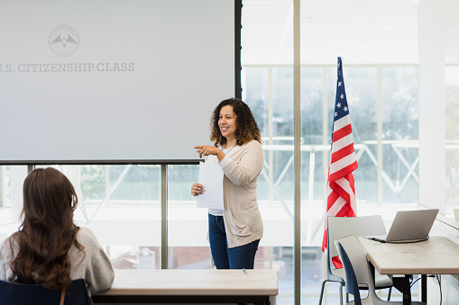The mid adult woman points to an unseen student as she teaches an American citizenship class.