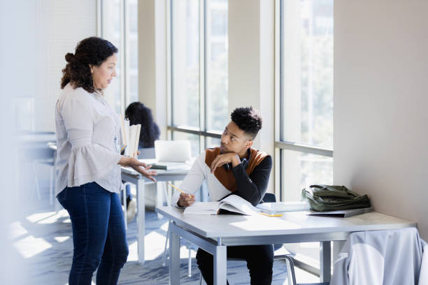 istock Male student listens as librarian answers question 1386085820