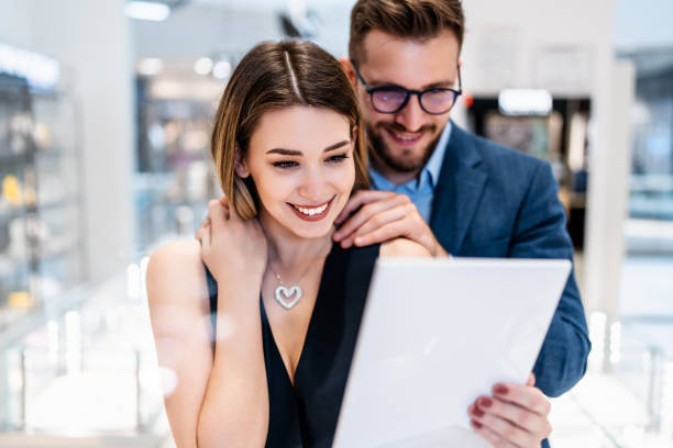 Beautiful couple in jewelry store Beautiful couple enjoying in shopping at modern jewelry store. Men fashion and elegance concept. jewelry store stock pictures, royalty-free photos & images