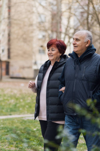 istock Active senior couple holding hands while walking in a park 1386088301