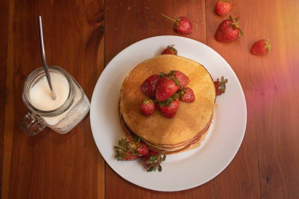 Plate of hot cakes and strawberries on a wood table stock photo