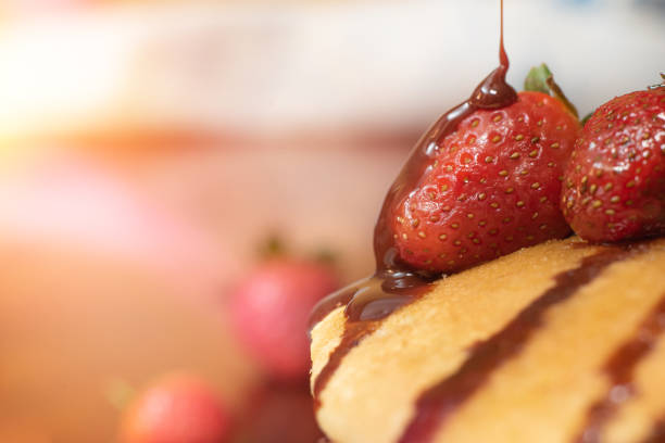 Closeup of a strawberry dripping chocolate syrup stock photo