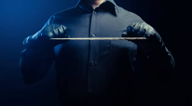 Strangler assassin man in shirt with rope. Photo of a shaded strangler assassin man in black shirt and leather gloves holding rope. serial killings photos stock pictures, royalty-free photos & images