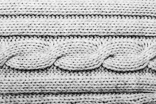 Texture backdrop photo of grey colored cable knitted fabric cloth.