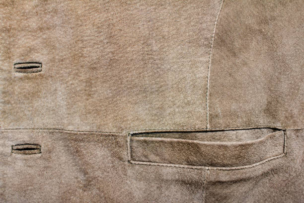 Brown colored suede material jacket texture. Texture backdrop photo of brown colored suede leather pocket and buttonholes. leather pocket clothing hide stock pictures, royalty-free photos & images