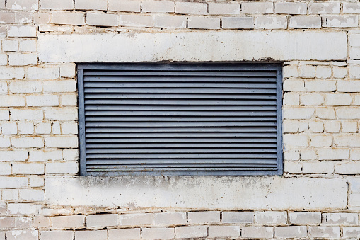 Photo texture of old ventilation metal hatch on brick wall.