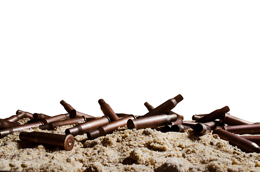 Isolated photo of metal bullet gun shells laying on sand surface.