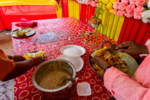 Photo of Blurred image of Howrah, West Bengal, India. Vog, prasad, or sacred worshipped food, being distributed to devotees, after worshipping idol of God Jagannath, Balaram and Suvodra inside pandal.