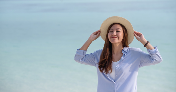 Portrait image of a beautiful young asian woman with blue sea water in background