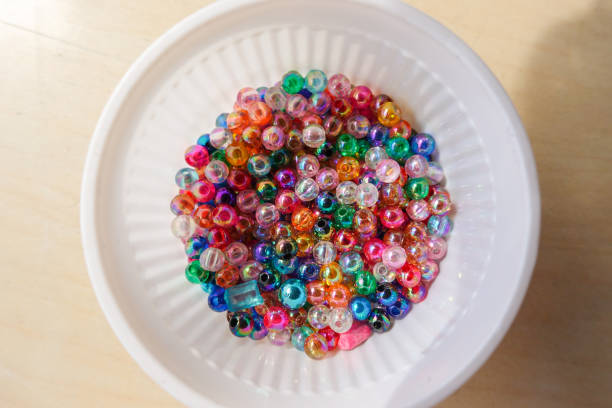Beads of various colors are placed in a white plastic glass.