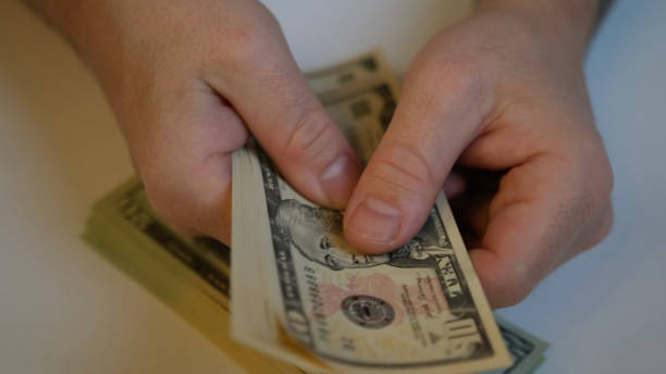 istock Male hands counting one hundred US dollars in tens 1386122505