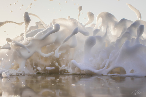 Full frame white ocean sea foam splashing onto beach shore