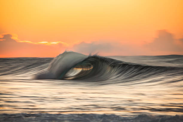 istock Beautiful slow shutter wave in front of gold and pink sky 1386135188