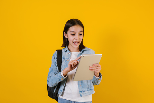 portrait of young hispanic child teen girl student with headphones listening music on a yellow background in Mexico Latin America