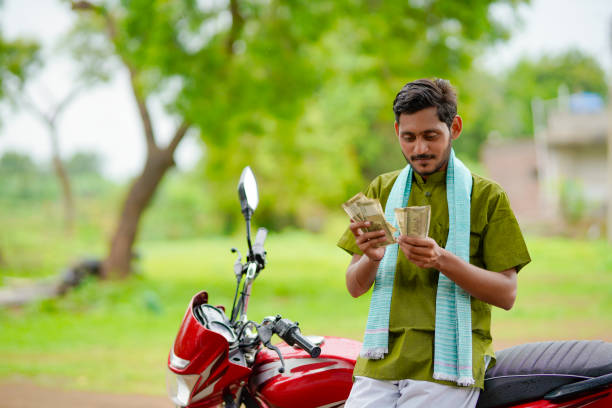 Indian farmer sitting on his new bike and showing money. stock photo