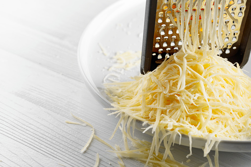 Grated cheese and grater. Concept: Italian cuisine, cheese, restaurant, and food. Copy space.