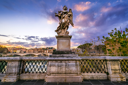 The sunset light envelops a statue from Bernini's workshop along Ponte Sant'Angelo in the Baroque heart of Rome