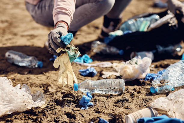 istock Close-up of environmentalist picking up trash while cleaning the nature. 1386170413