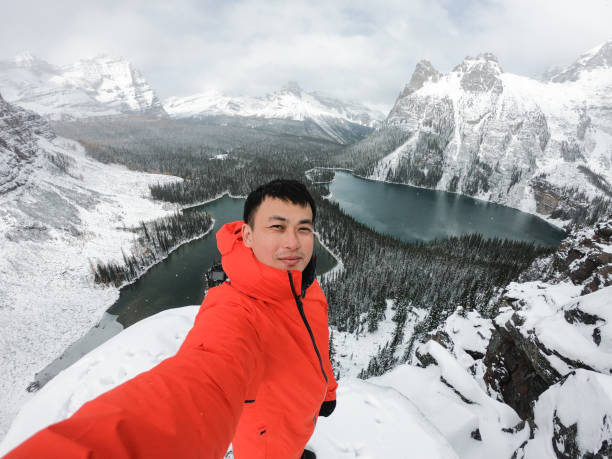 Asian hiker man selfie by camera during photograph on mountain peak in winter at Opabin Plateau Happy asian hiker man selfie by camera during photograph on mountain peak in winter at Opabin Plateau, Yoho national park, AB, Canada irish travellers photos stock pictures, royalty-free photos & images