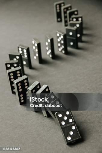 istock Black dominoes chain on dark table background 1386173362