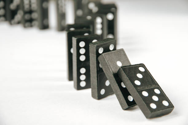 istock Black dominoes chain on white table background 1386173365