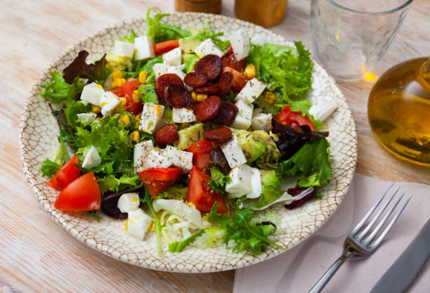 Traditional Catalonian food, salad with fried sausages, avocado and cheese on a ceramic plate