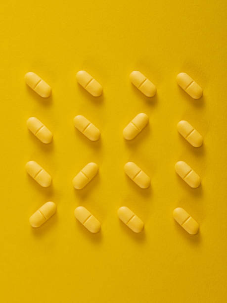 istock Pills in a row on yellow background. Vertical composition. 1386174110
