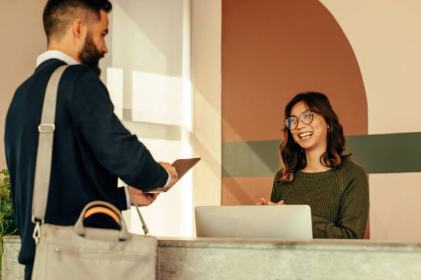 istock Happy receptionist assisting a man with signing in to an office 1386175831