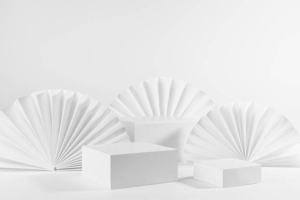 istock Set of three different size white rectangle podiums mockup for presentation, displaying cosmetic product or goods with ribbed paper fans, blinds in elegant modern style, side view, corner, 3d. 1386175947