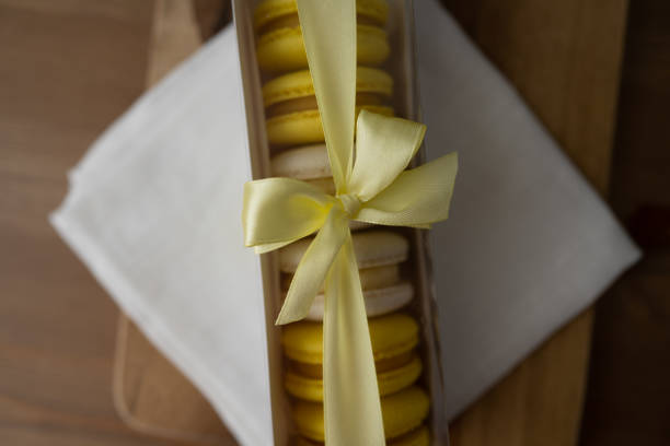 A box of delicious and appetizing macaroons, a beautiful baking package with a ribbon on a wooden table.