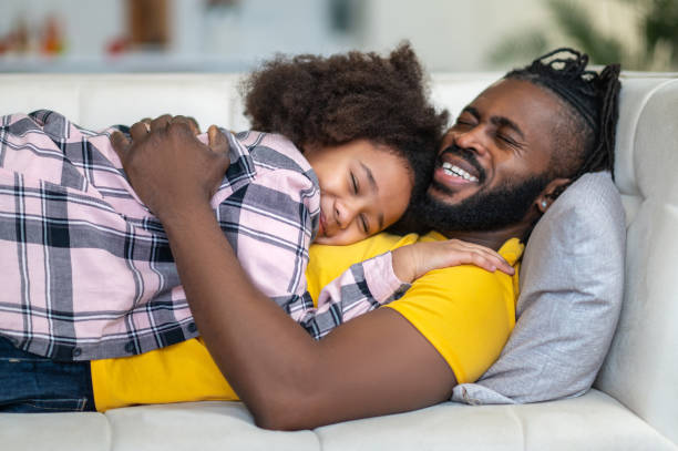 istock Happy man hugging daughter lying on sofa 1386176534