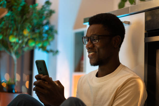 istock Young Happy Black Guy Using Smartphone While Relaxing And Spending Leisure Time At Cozy Home 1386177433