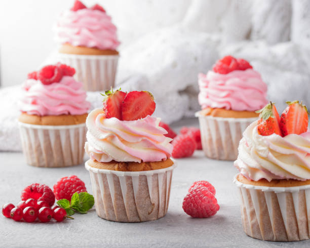 istock Pink cupcakes with cream and fresh berries 1386177959