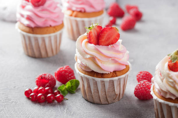 istock Pink cupcakes with cream and fresh berries 1386178109