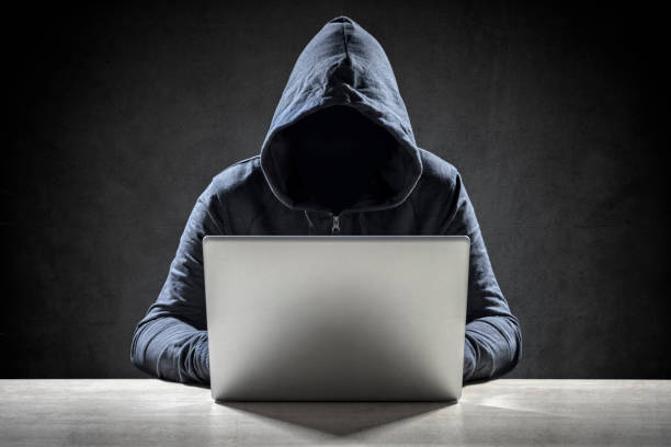 Computer hacker stealing data from a laptop Computer hacker stealing data from a laptop concept for network security, identity theft and computer crime scammer stock pictures, royalty-free photos & images