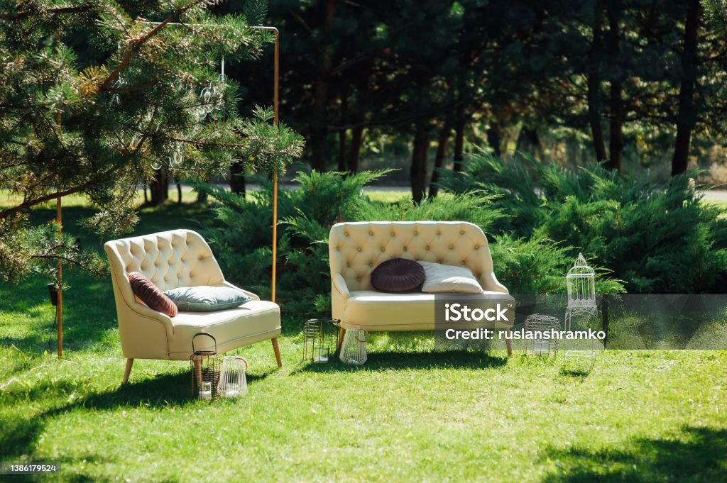 Cozy sofas for relaxing in the garden near the house on the grass. Relax and rest Cozy wicker sofas for relaxing in the garden near the house on the grass. Relax and rest Back Yard Stock Photo
