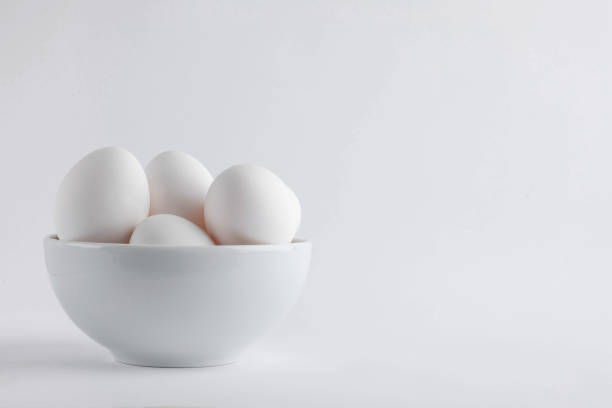 istock Chicken white fresh eggs from free-range in egg cups with natural feathers on light background. Concept farm products and natural nutrition, rural and healthy dairy products Copy space or empty place 1386181609