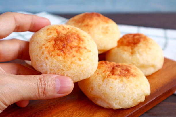 Closeup hand picking a fresh baked delectable Brazilian cheese bread or Pao de Queijo