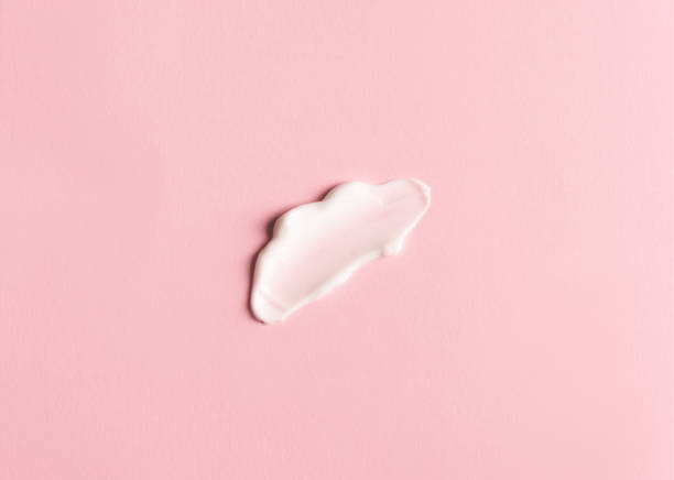 istock Smear of white face cream on pink background 1386183232