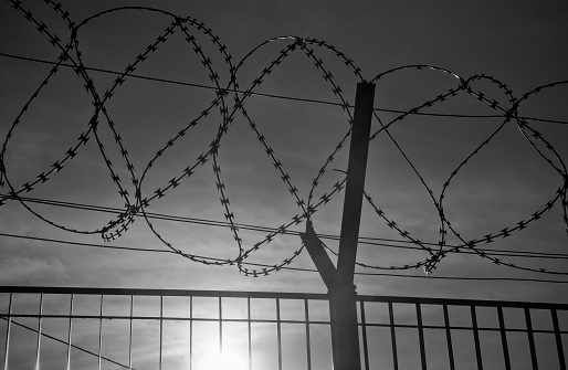 The Fence - Low sun behind razor wire (NATO-Draht). Symbol of hope for a better future.