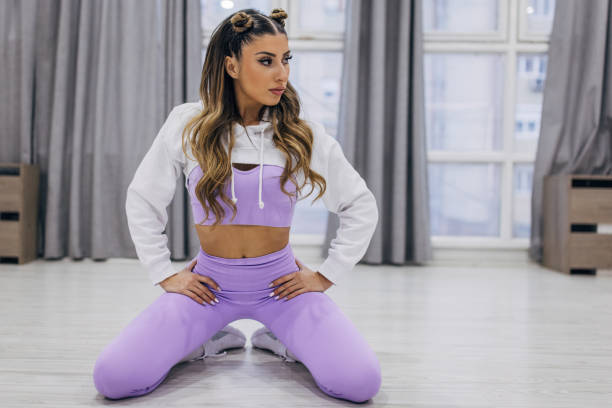 Portrait of a fit young woman kneeling alone in gym.