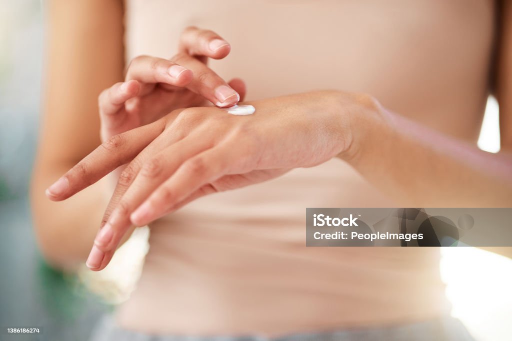 Shot of an unrecognizable woman using cream at home Just a little bit Suntan Lotion Stock Photo