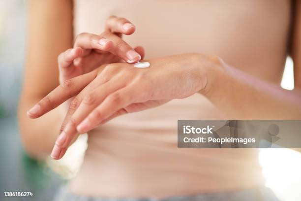 Shot Of An Unrecognizable Woman Using Cream At Home Stock Photo - Download Image Now